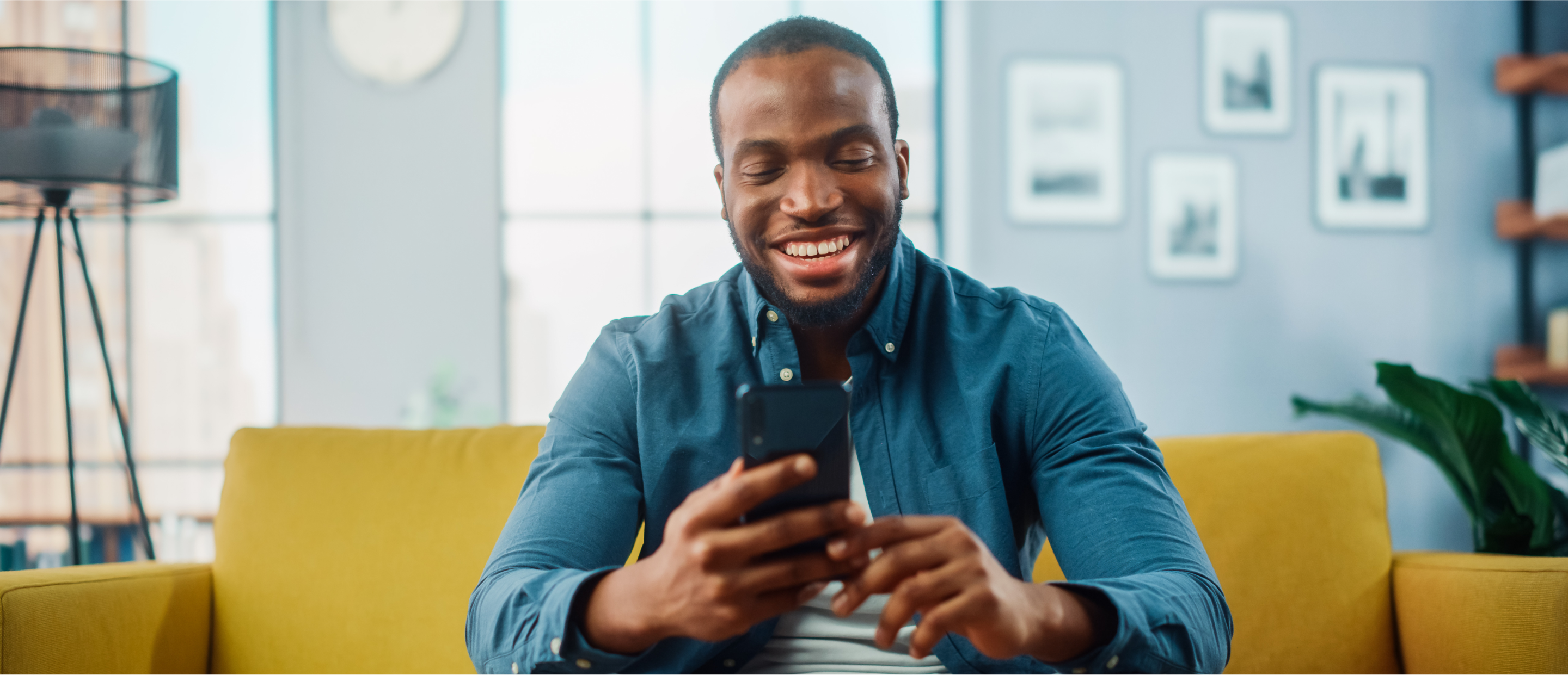 a man on a couch smiling at his phone