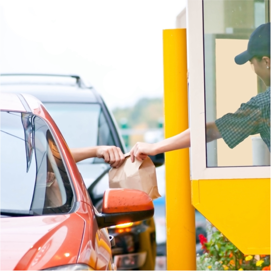 Image of a person giving food to a customer in a drive-through lane